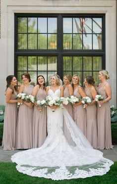 a bride and her bridals posing in front of a window with their bouquets