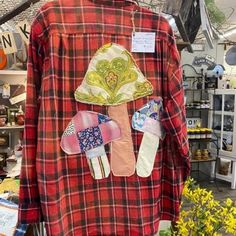 a red and black plaid shirt with patchwork patches on the chest, some flowers in vases next to it