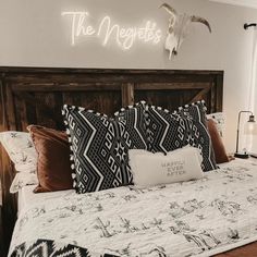 a bed with black and white pillows and a cow skull on the wall above it