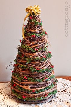 a christmas tree made out of branches and twigs on a doily table with a gold bow