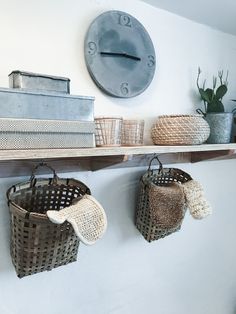 some baskets are hanging on the wall near a clock