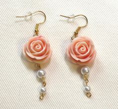 These handcrafted earrings feature delicate peach roses paired with classic white pearls, creating a romantic and feminine accessory. Details: Gold-tone fish hook earwires for easy wear Detailed resin rose beads in a soft peach color, approximately 15mm in diameter Three graduated white pearl beads, ranging from about 3-6mm Total drop length of approximately 2 inches (5 cm) Perfect for adding a touch of vintage-inspired charm to any outfit. These versatile earrings are ideal for weddings, specia Fairycore Accessories, Floral Tea Party, Earrings Cottagecore, Coquette Jewelry, Cottagecore Earrings, Rose Beads, Diy Jewelry Earrings, Cottagecore Coquette, Color Earrings