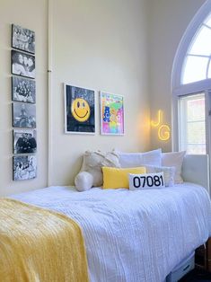 a bedroom with pictures on the wall and a smiley face pillow in the bed room