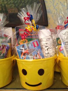 two yellow buckets filled with toys and other items sitting on a table next to each other