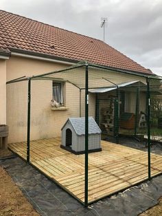 a dog house with a caged in area next to it and a wooden deck