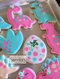 decorated cookies in the shape of animals on a baking sheet with pink, blue and green icing