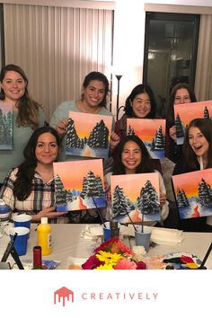 a group of women holding up paintings at a table