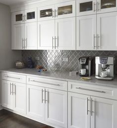 a kitchen with white cabinets and stainless steel backsplash tiles on the countertops