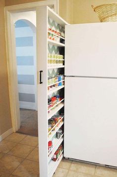 a white refrigerator freezer sitting inside of a kitchen next to a pantry filled with food