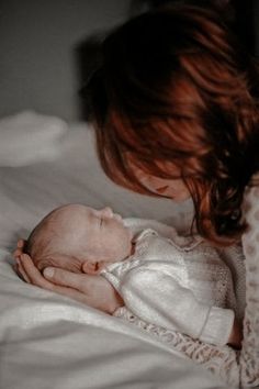 a woman holding a baby on top of a bed