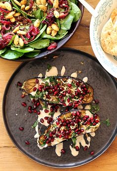 two plates filled with food sitting on top of a wooden table next to other dishes