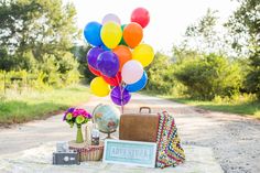 a bunch of balloons that are on top of a blanket in the dirt near a road