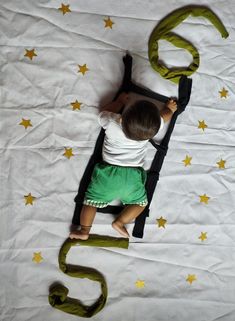 a small child laying on top of a bed next to a green snake and numbers