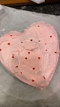 a heart shaped cake sitting on top of a piece of wax paper covered in pink frosting