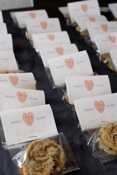 there are many cookies in plastic bags on the table with name tags attached to them