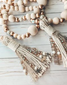 a necklace with tassels and beads on a white wooden table next to it