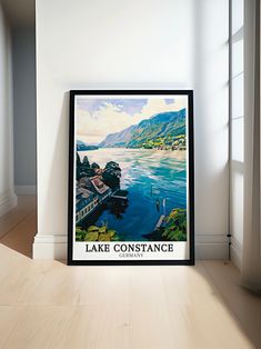 there is a framed poster on the floor in front of a window that says lake constantce