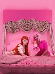 two beautiful women laying on top of a pink bed