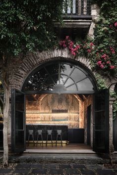 an outdoor bar is lit up with flowers and greenery on either side of it