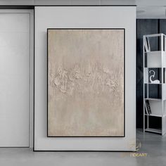 an abstract painting hangs on the wall next to a white bookcase and shelving unit