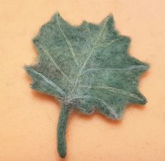 a green leaf that is sitting on the ground with some wool in it's center