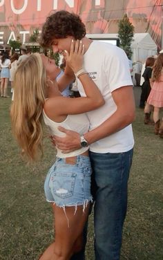 a man and woman kissing each other in front of a crowd at an outdoor music festival