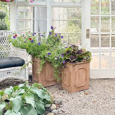 two wooden planters sitting in front of a window filled with purple and red flowers