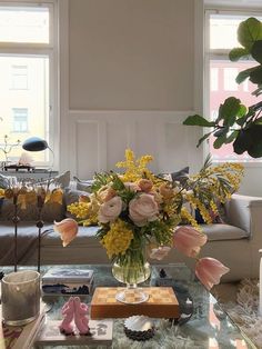 a living room filled with lots of furniture and flowers on top of a glass table