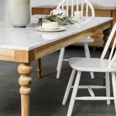 a table with white chairs and a vase on it's end next to the dining room table