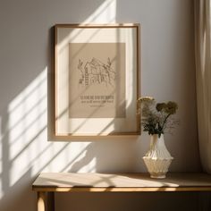 a vase with flowers sitting on a table in front of a framed poster and window