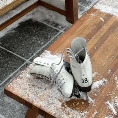 a pair of ice skates sitting on top of a wooden bench covered in snow