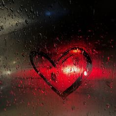 a heart shaped object sitting on top of a wet window