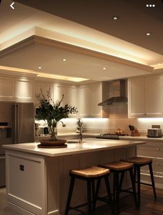 a kitchen with two stools in front of an island and lights on the ceiling