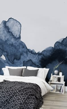 a bedroom with blue watercolor paint on the wall and white linen bedding, nightstands and clock