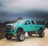 a bright blue pickup truck parked on the side of a dirt road under a cloudy sky