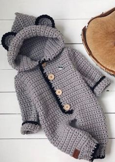 a crocheted coat and hat are laying on the floor next to a piece of wood