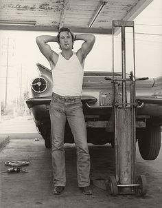 a man standing in front of a car with his hands on his head