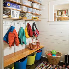 the inside of a room with several buckets and baskets on shelves next to a rug