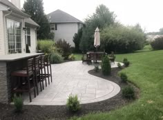 a patio with chairs and an umbrella in the middle of it next to a house