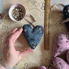 someone is holding a heart shaped decoration next to some other items on a lace tablecloth