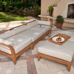 a couch and ottoman sitting on top of a brick patio next to a fire place