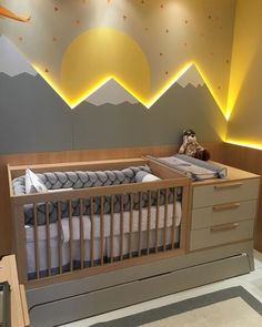 a baby crib in the middle of a room with mountains painted on the wall