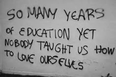 graffiti written on the side of a building reads so many years of education yet nobody taught us how to love ourselves