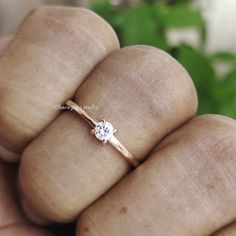 a close up of a person's hand holding a ring with a diamond on it