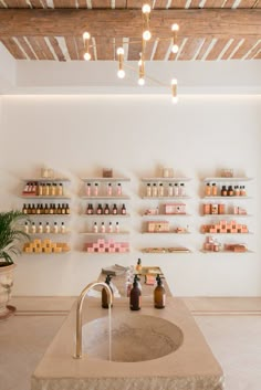 a bathroom sink sitting under a faucet next to a wall mounted shelf filled with bottles