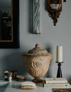 an ornate urn sits on a table next to books, candles and other items