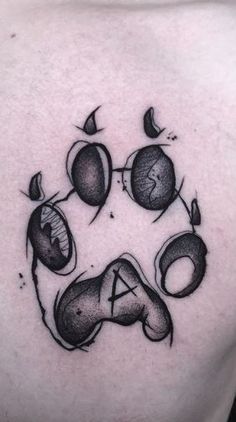 a dog's paw with balloons and letters tattoo on the back of his chest