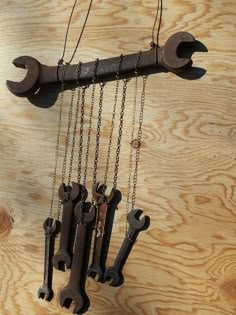 several wrenches hanging from chains on a wooden wall