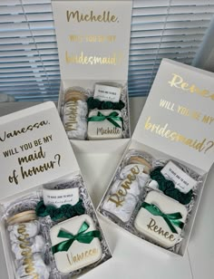 three decorated cookies in boxes with gold lettering and green bows are on the table next to two cards that say will you be my bridesmaid?, will you be my