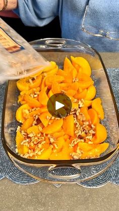 a glass dish filled with food on top of a blue tablecloth covered table next to a person